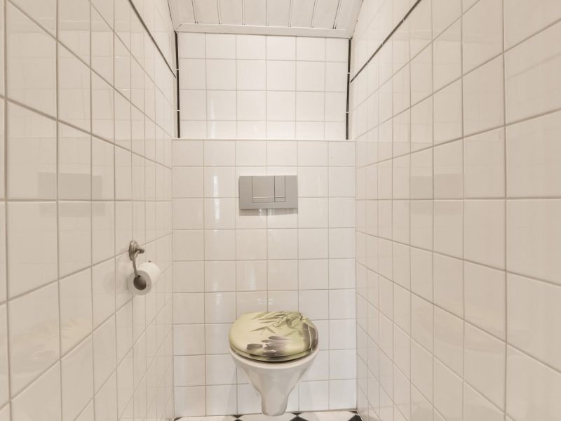 a tiled bathroom with black and white tiles on the floor, along with an open toilet in the center of the room